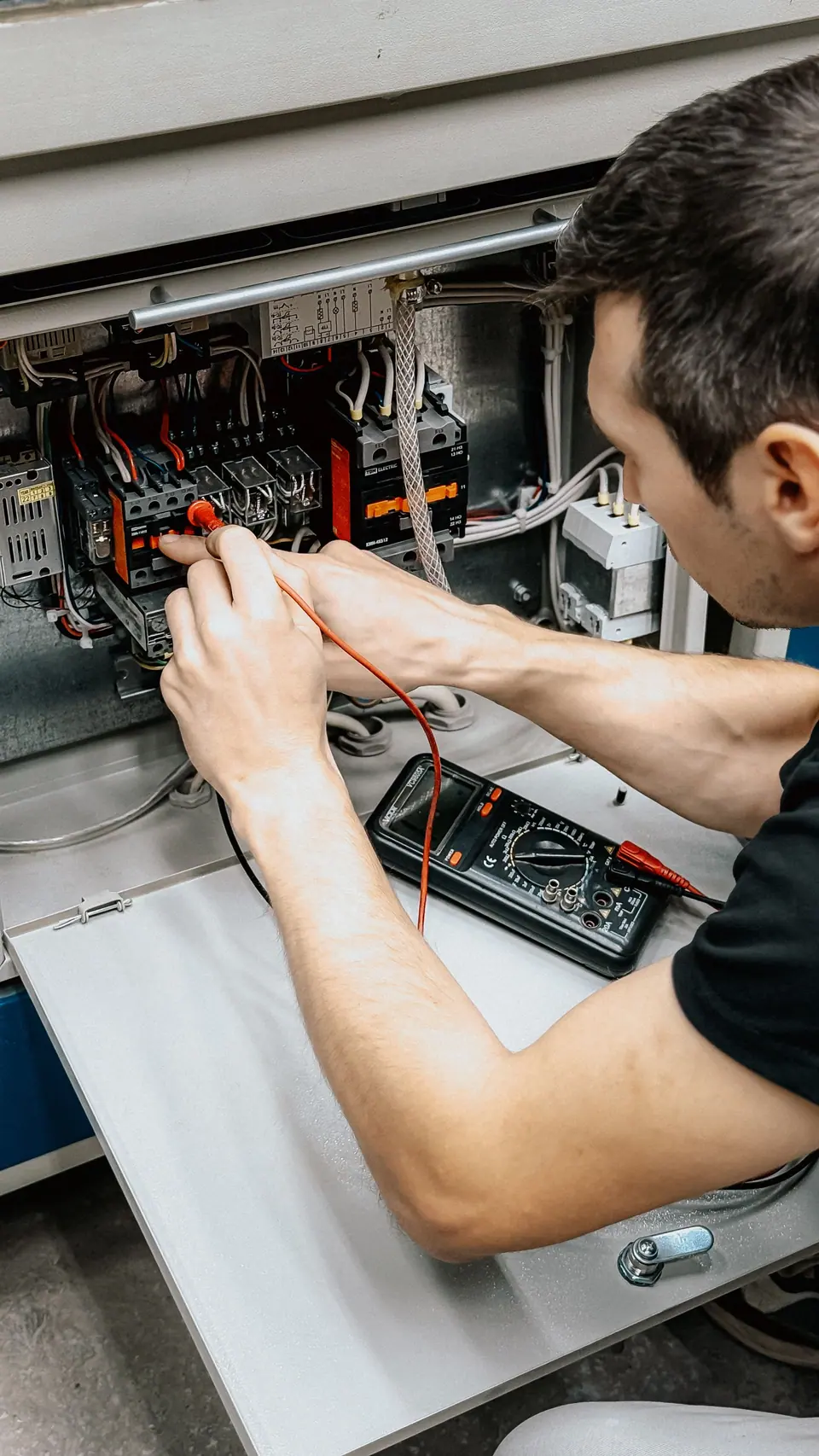 Electrician testing connections inside an electrical panel